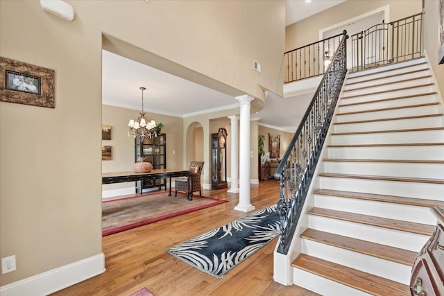 entrance foyer featuring stairs, baseboards, ornate columns, and wood finished floors