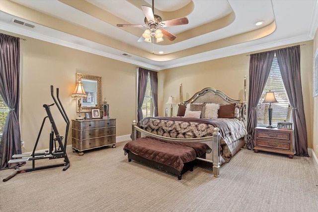 carpeted bedroom with a tray ceiling, visible vents, crown molding, and multiple windows