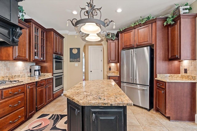 kitchen featuring tasteful backsplash, appliances with stainless steel finishes, glass insert cabinets, a kitchen island, and light stone countertops