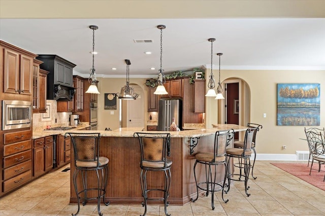 kitchen featuring arched walkways, hanging light fixtures, and a large island with sink