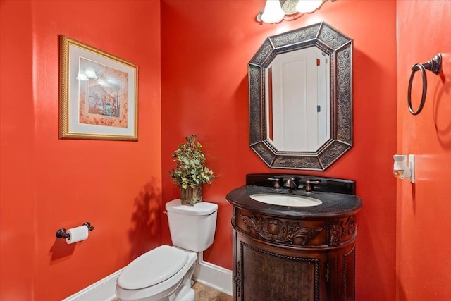 bathroom featuring toilet, vanity, and baseboards