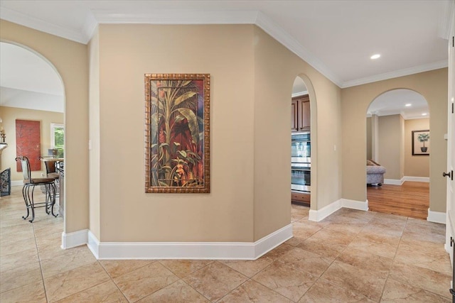 hall featuring ornamental molding, arched walkways, and baseboards