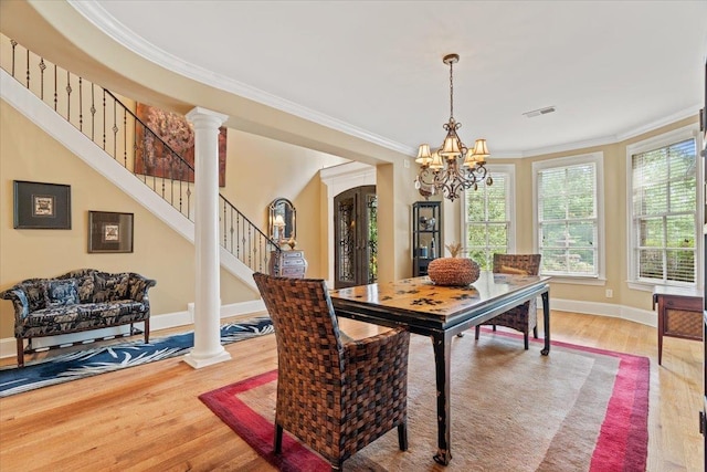 dining room featuring stairs, crown molding, ornate columns, and wood finished floors