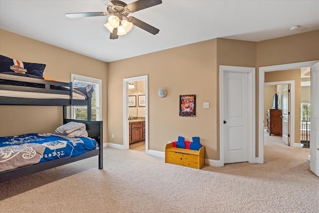 bedroom featuring baseboards, connected bathroom, a ceiling fan, and light colored carpet