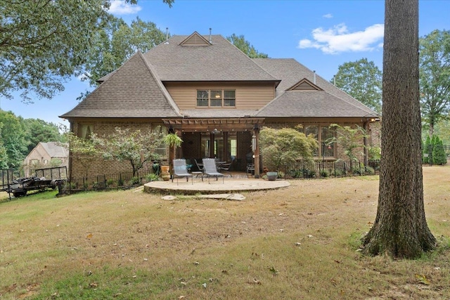 back of house featuring a yard, brick siding, and a patio