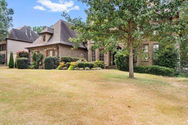 view of front of house with brick siding, a front lawn, and a shingled roof