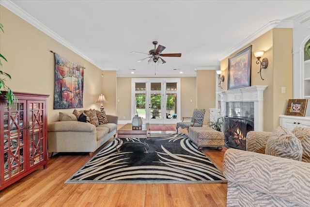 living room with light wood finished floors, crown molding, a tiled fireplace, and french doors