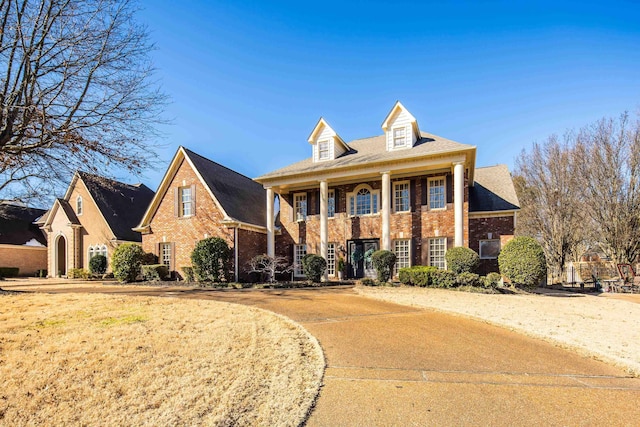 greek revival inspired property with brick siding and a front yard