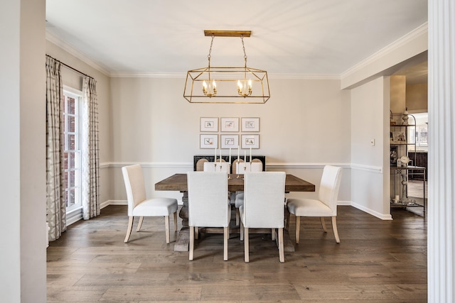 dining room with ornamental molding, dark wood-style flooring, an inviting chandelier, and baseboards