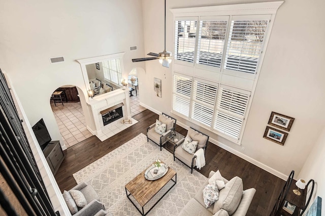 living area featuring visible vents, baseboards, dark wood-style floors, ceiling fan, and a fireplace