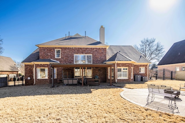 rear view of house with a patio, brick siding, a chimney, and fence