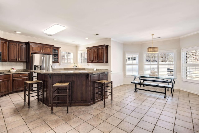 kitchen featuring hanging light fixtures, a breakfast bar, dark brown cabinetry, and a center island