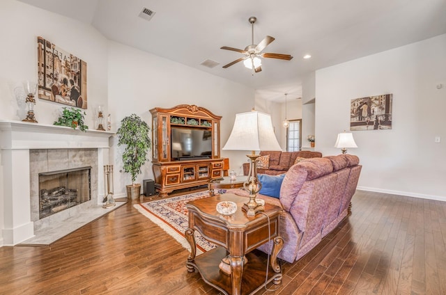 living room featuring dark wood-type flooring, a fireplace, visible vents, and a ceiling fan