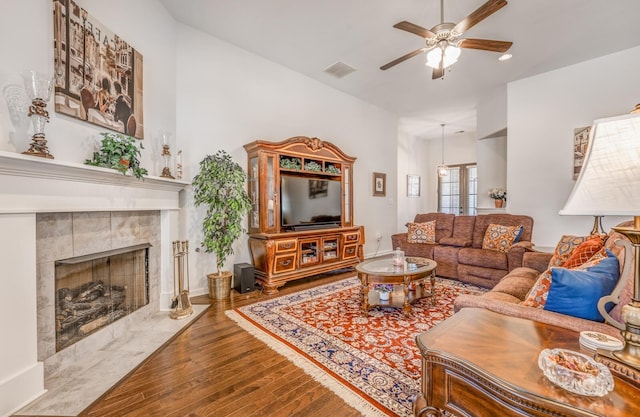 living room with a high end fireplace, visible vents, ceiling fan, and wood finished floors