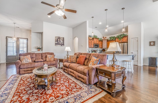 living room featuring baseboards, arched walkways, a ceiling fan, lofted ceiling, and wood finished floors