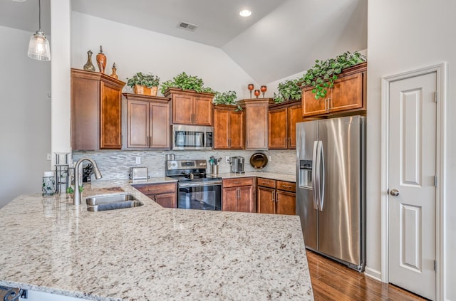 kitchen with visible vents, brown cabinetry, a peninsula, stainless steel appliances, and a sink