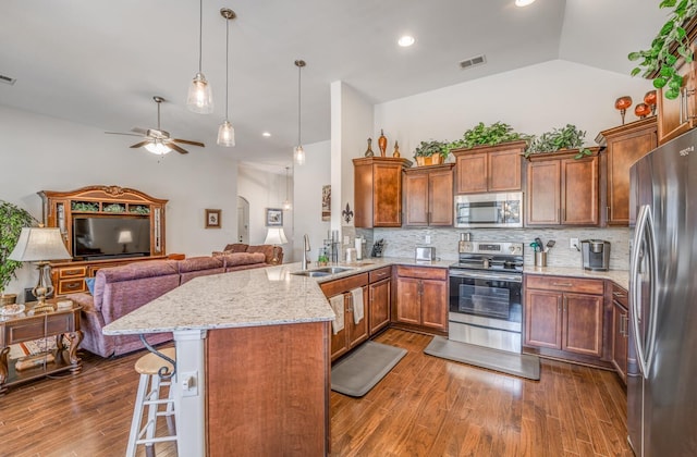 kitchen with a kitchen breakfast bar, open floor plan, a peninsula, stainless steel appliances, and a sink