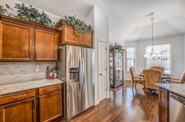 kitchen featuring light stone counters, dark wood-style flooring, decorative light fixtures, visible vents, and appliances with stainless steel finishes