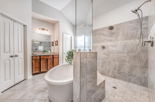 bathroom with a freestanding bath, a walk in shower, lofted ceiling, and vanity