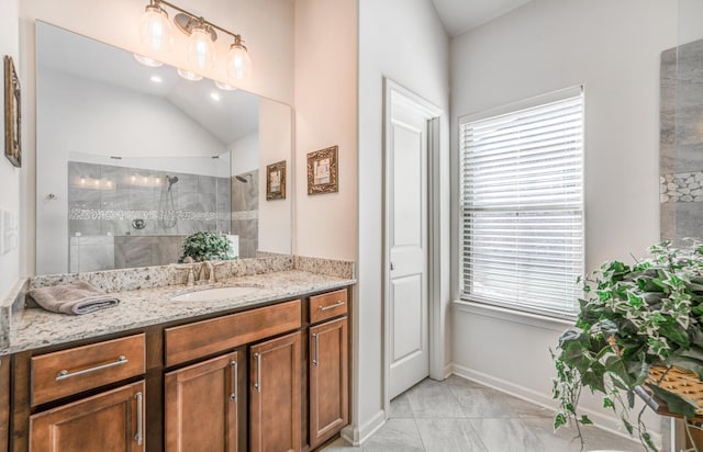 bathroom featuring lofted ceiling, baseboards, walk in shower, and vanity