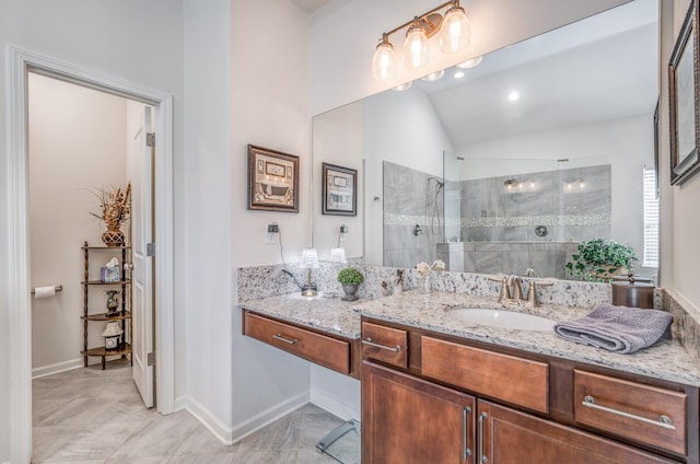 bathroom featuring vaulted ceiling, baseboards, a walk in shower, and vanity