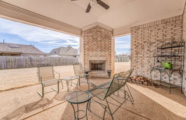 view of patio featuring ceiling fan, an outdoor brick fireplace, and fence