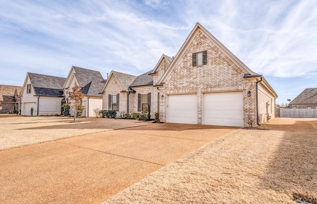 view of front of house featuring concrete driveway, brick siding, and fence