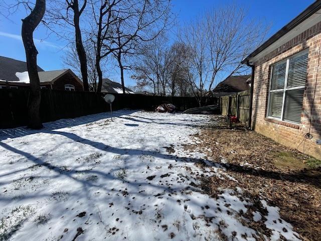 yard covered in snow featuring fence