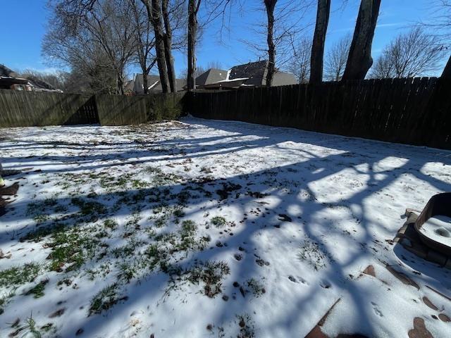 snowy yard featuring fence