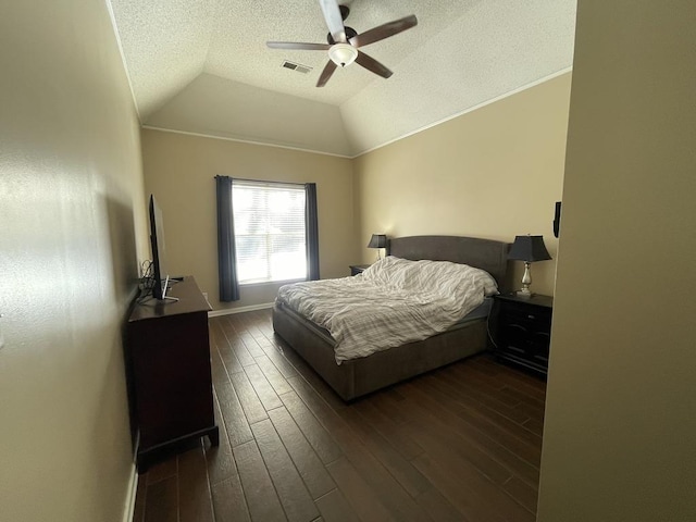 bedroom with vaulted ceiling, a textured ceiling, dark wood finished floors, and visible vents