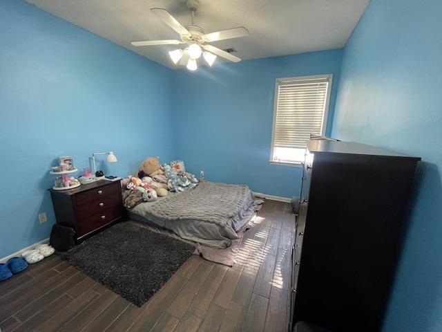 bedroom featuring a ceiling fan, dark wood-style flooring, and baseboards