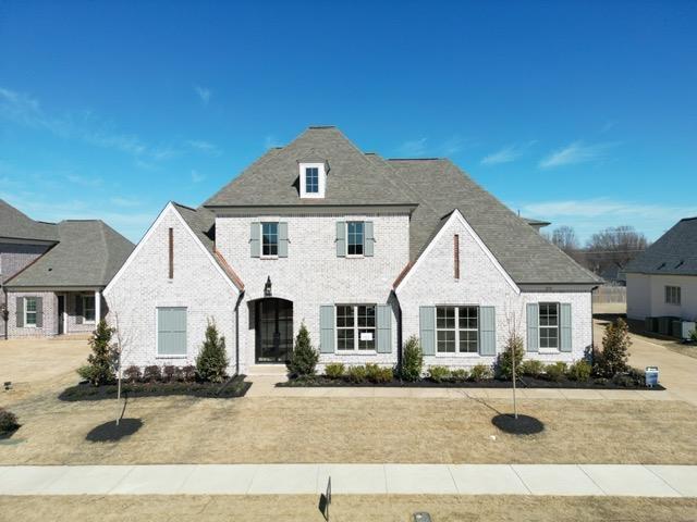 french country style house featuring brick siding and a front yard