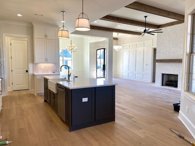 kitchen with light countertops, light wood finished floors, a brick fireplace, and white cabinetry