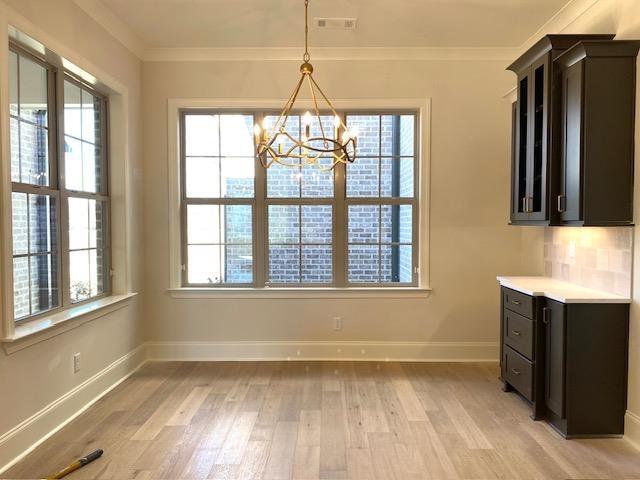 unfurnished dining area featuring ornamental molding, plenty of natural light, and light wood finished floors