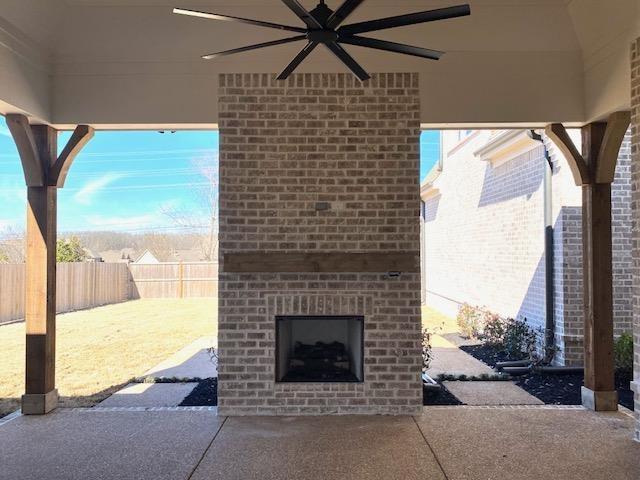 view of patio / terrace with an outdoor brick fireplace, a fenced backyard, and ceiling fan