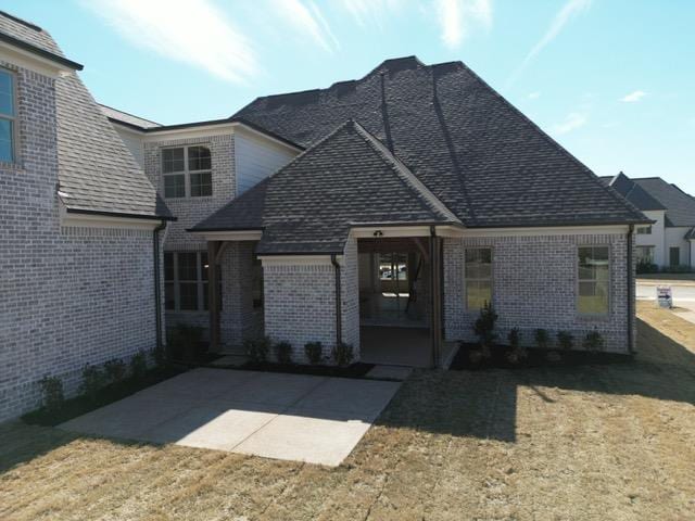 view of front of property featuring a patio area, brick siding, and a front lawn