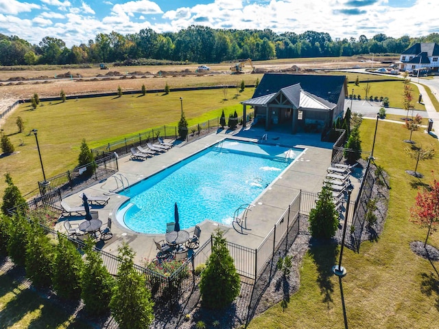 pool featuring a yard, a patio area, fence, and a rural view