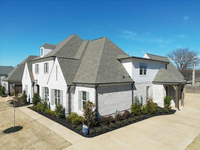 exterior space with a shingled roof and brick siding