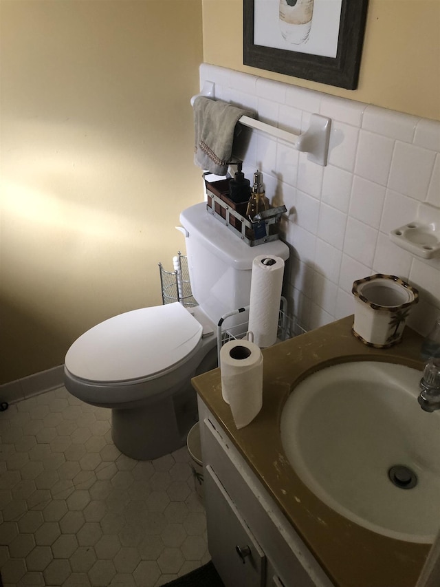 half bathroom featuring toilet, tile walls, and vanity