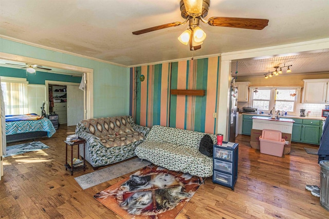 living room featuring ornamental molding, light wood-style floors, and a ceiling fan