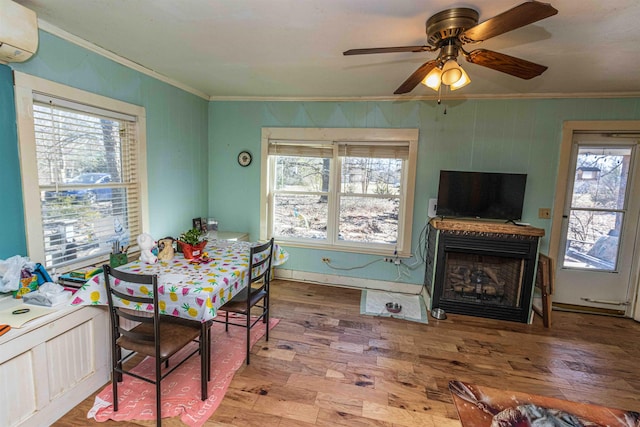 dining room with a fireplace, wood finished floors, crown molding, and a wall mounted AC