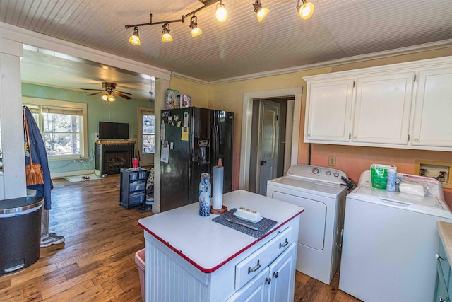 washroom with wood finished floors, a fireplace, washing machine and dryer, and cabinet space