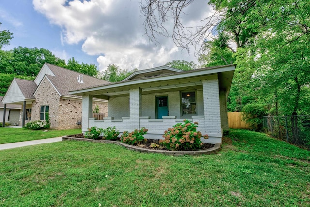 view of front of house featuring a porch, a front yard, brick siding, and fence