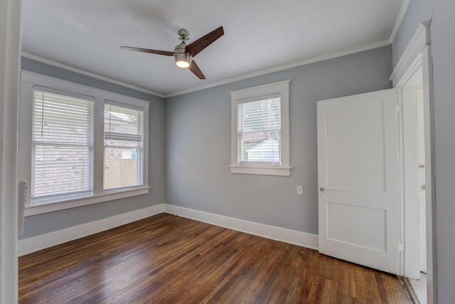 spare room with ornamental molding, dark wood-type flooring, a ceiling fan, and baseboards