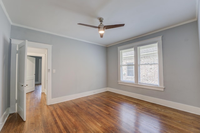 spare room with ornamental molding, baseboards, and wood finished floors