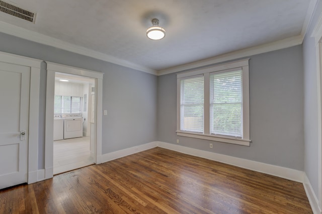 spare room featuring baseboards, visible vents, washer and clothes dryer, ornamental molding, and dark wood-type flooring