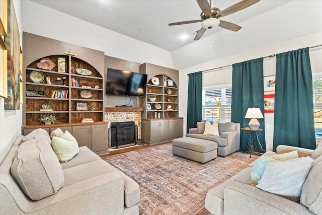 living room featuring built in features, a brick fireplace, and a ceiling fan