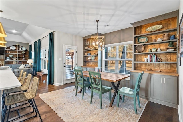 dining room featuring built in features, visible vents, dark wood-type flooring, vaulted ceiling, and a chandelier