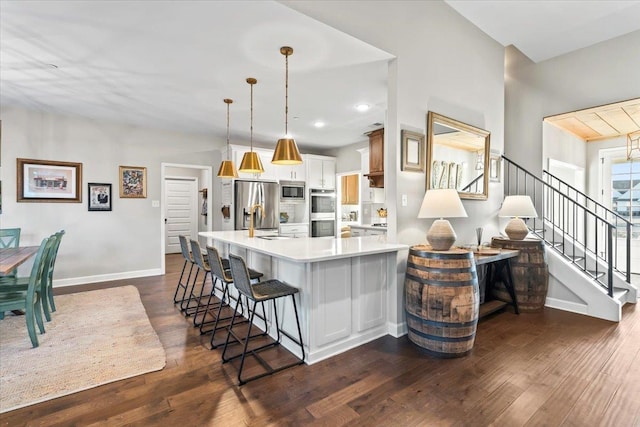 kitchen with appliances with stainless steel finishes, dark wood-style flooring, light countertops, and a peninsula