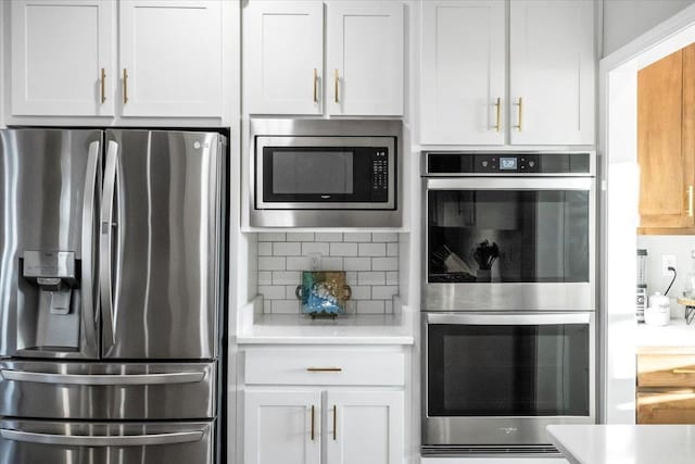 kitchen featuring stainless steel appliances, backsplash, light countertops, and white cabinets